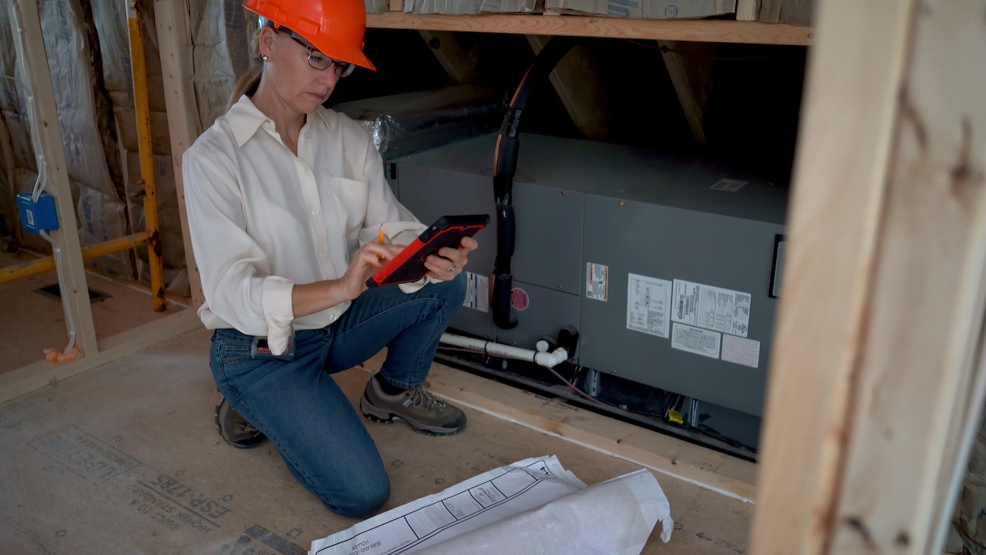 Closeup of female mechanical engineer checking HVAC furnace or air conditioning unit in a new home construction.